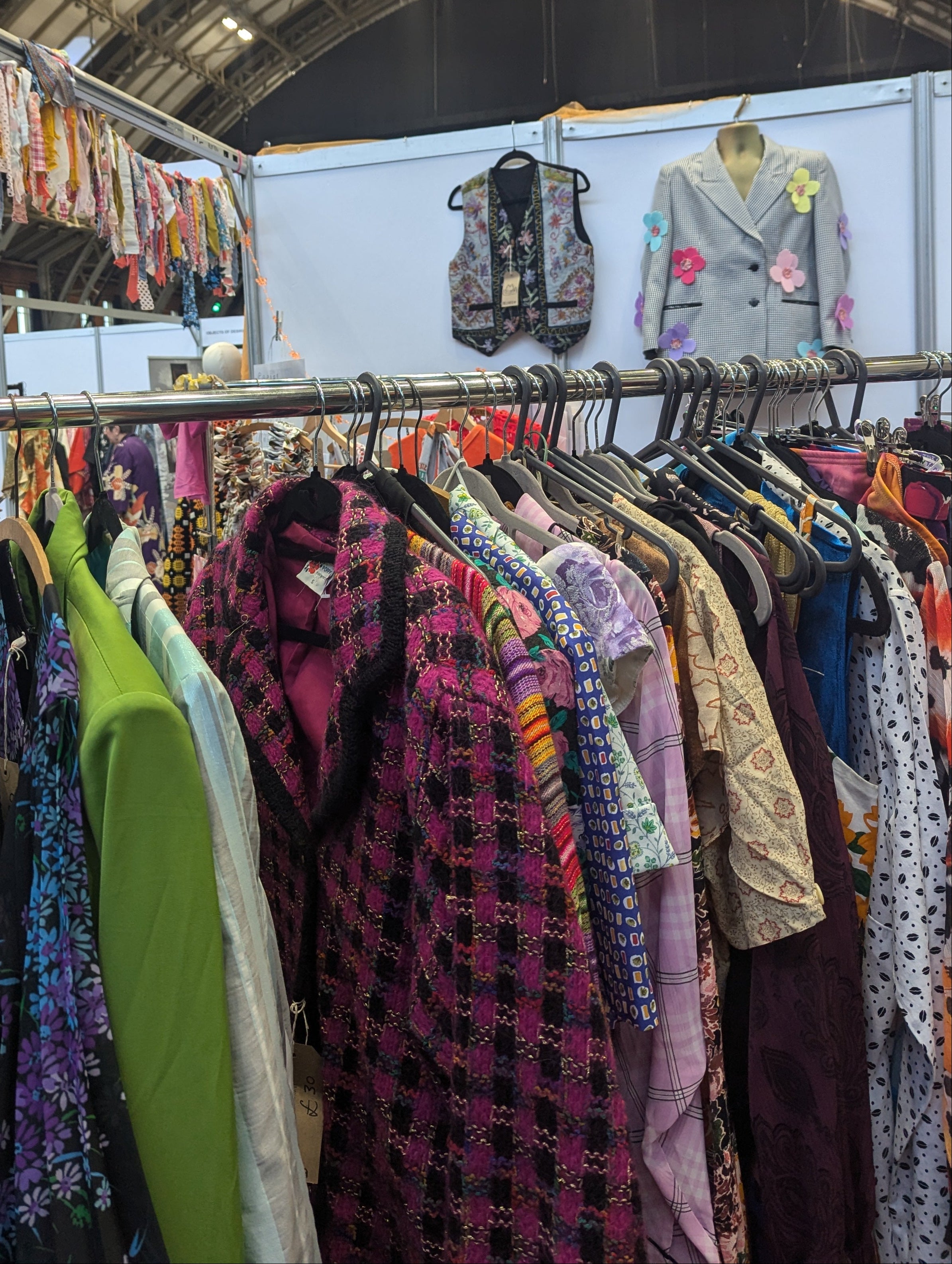 Vintage clothing on racks with a colorful display in the background.